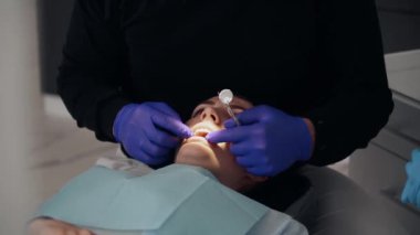 Diş kliniğinde koruyucu maskeli iki doktor hasta kıza hizmet ediyor. İş Dişçiliği. Sağlık ve Tıp Konsepti.