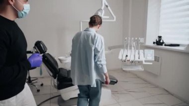 Diş kliniğinde koruyucu maskeli iki doktor hasta kıza hizmet ediyor. İş Dişçiliği. Sağlık ve Tıp Konsepti.