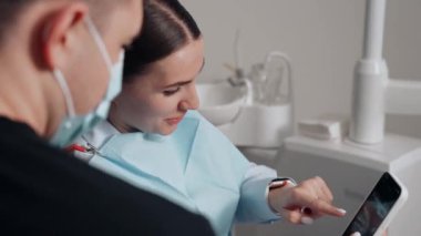 Diş kliniğinde koruyucu maskeli iki doktor hasta kıza hizmet ediyor. İş Dişçiliği. Sağlık ve Tıp Konsepti.