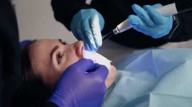 Diş kliniğinde koruyucu maskeli iki doktor hasta kıza hizmet ediyor. İş Dişçiliği. Sağlık ve Tıp Konsepti.