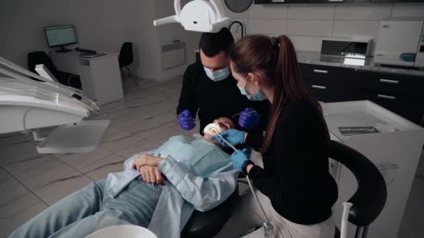 Два Врача Мужчина Женщина Защитных Масках Стоматологической Клинике Обслуживают Пациентку — стоковое видео