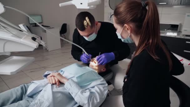 歯科医院の保護マスクの男と女の2人の医者は 患者の少女に奉仕します 歯医者だ 医療の概念 — ストック動画