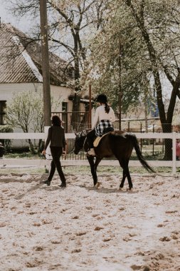 Kıza ata binmeyi öğreten bir kadın eğitmen. At sırtında at binmeyi öğrenen bir kadın binici. Aktif yaşam tarzı ve boş zaman aktivite kavramı