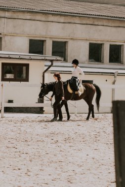 Kıza ata binmeyi öğreten bir kadın eğitmen. At sırtında at binmeyi öğrenen bir kadın binici. Aktif yaşam tarzı ve boş zaman aktivite kavramı