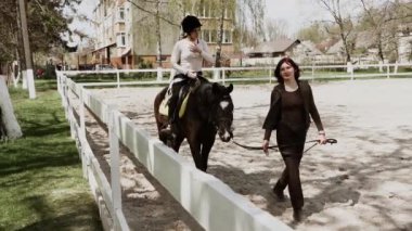 Miğferli genç, güzel bir kadın ata binmeyi öğreniyor. Ata binme sporu. Aktif yaşam tarzı ve eğlence aktivitesi konsepti.