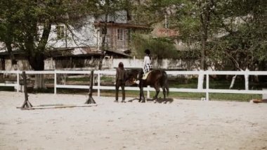 Miğferli genç, güzel bir kadın ata binmeyi öğreniyor. Ata binme sporu. Aktif yaşam tarzı ve eğlence aktivitesi konsepti.