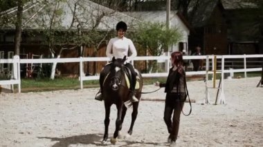 Miğferli genç, güzel bir kadın ata binmeyi öğreniyor. Ata binme sporu. Aktif yaşam tarzı ve eğlence aktivitesi konsepti.