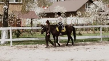 Miğferli genç, güzel bir kadın ata binmeyi öğreniyor. Ata binme sporu. Aktif yaşam tarzı ve eğlence aktivitesi konsepti.