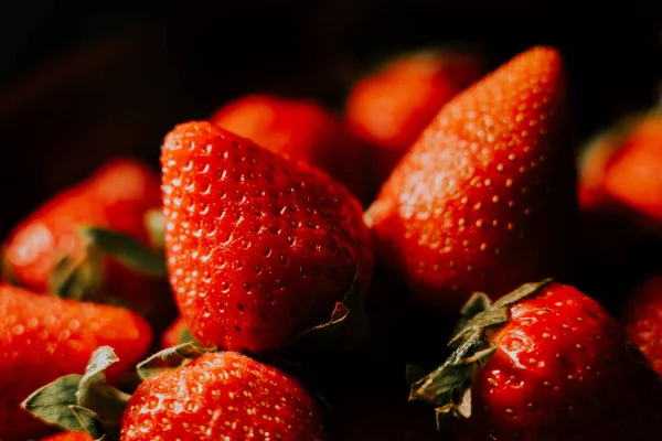 Siyah arka planda dönen çilekler. Taze, organik kırmızı çilekli çiğ vejetaryen yaz atıştırması.