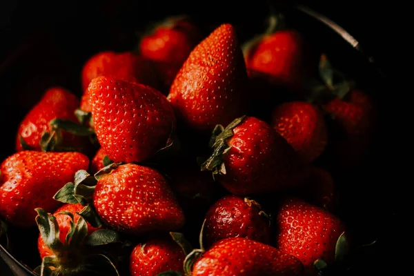 Siyah arka planda dönen çilekler. Taze, organik kırmızı çilekli çiğ vejetaryen yaz atıştırması.
