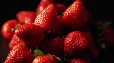 Çilekler siyah arka planda dönüyor. 4K 'de taze organik kırmızı çilek. Çiğ vejetaryen yaz atıştırması