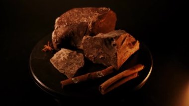 Çikolata. Koyu renkli çikolata parçaları koyu arka planda döner, döner. Gurme tatlı malzemesi. Şekerleme, şekerleme konsepti. 4K