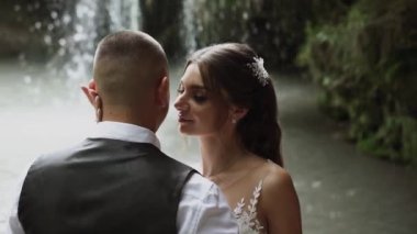 Genç çift aşık gelin ve damat, düğün günü bir dağ şelalesinin yanında. Mutluluğun ve aşkın tadını çıkar.