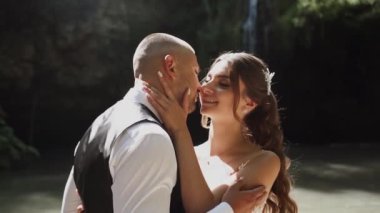 Genç çift aşık gelin ve damat, düğün günü bir dağ şelalesinin yanında. Mutluluğun ve aşkın tadını çıkar.