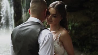 Genç çift aşık gelin ve damat, düğün günü bir dağ şelalesinin yanında. Mutluluğun ve aşkın tadını çıkar.