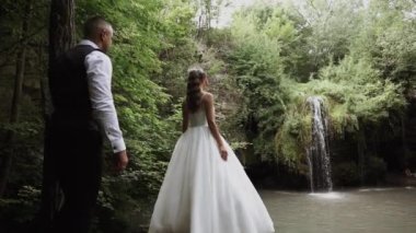 Genç çift aşık gelin ve damat, düğün günü bir dağ şelalesinin yanında. Mutluluğun ve aşkın tadını çıkar.