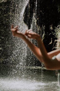 Bir dağ şelalesinin yanında poz veren turkuaz elbiseli güzel bir manken. Vahşi yaşam kavramı.