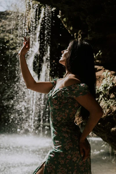 stock image Beautiful model in a turquoise dress posing near a mountain waterfall.Wildlife concept