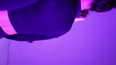 İki sporcu kız stüdyoda neon ışıkta spor yapıyor.