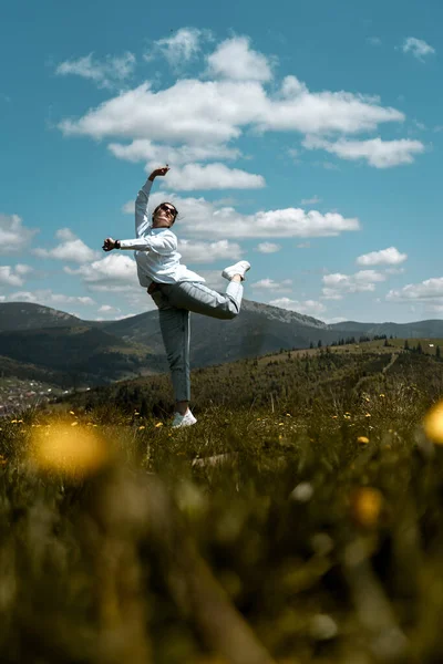 stock image Stylish woman in a white shirt and glasses posing against the backdrop of mountains