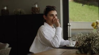 Güzel bir kadın kahve içer ve pencereden Karpat Dağları 'na uzanan bir restoranın manzarasının tadını çıkarır.