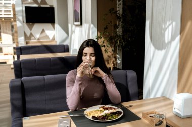 Güzel bir manzarası olan güzel bir kadın kahvaltı yapıyor.