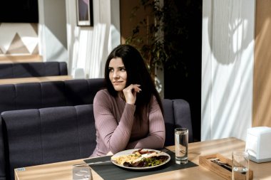 Güzel bir manzarası olan güzel bir kadın kahvaltı yapıyor.