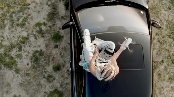 戴眼镜的时髦女人在日落时坐在车顶上发射无人驾驶飞机 无人机试点概念 — 图库视频影像