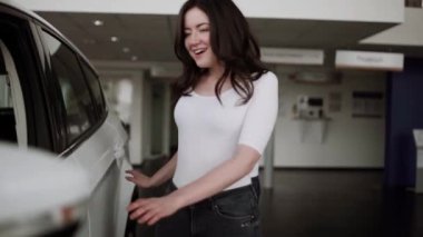 Otomobil satış merkezinde. Araba satıcısı genç bir aileye yeni otomobil satıyor. Araba galerisinde yeni bir araba seçen genç ve güzel bir çift.