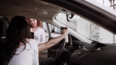 Otomobil satış merkezinde. Araba satıcısı genç bir aileye yeni otomobil satıyor. Araba galerisinde yeni bir araba seçen genç ve güzel bir çift.