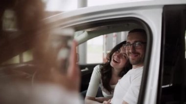 Otomobil satış merkezinde. Araba satıcısı genç bir aileye yeni otomobil satıyor. Araba galerisinde yeni bir araba seçen genç ve güzel bir çift.