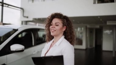 Otomobil satış merkezinde. Araba satıcısı genç bir aileye yeni otomobil satıyor. Araba galerisinde yeni bir araba seçen genç ve güzel bir çift.