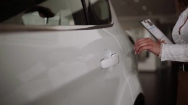 Otomobil satış merkezinde. Araba satıcısı genç bir aileye yeni otomobil satıyor. Araba galerisinde yeni bir araba seçen genç ve güzel bir çift.