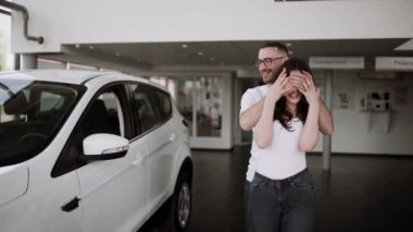 Otomobil satış merkezinde. Araba satıcısı genç bir aileye yeni otomobil satıyor. Araba galerisinde yeni bir araba seçen genç ve güzel bir çift.