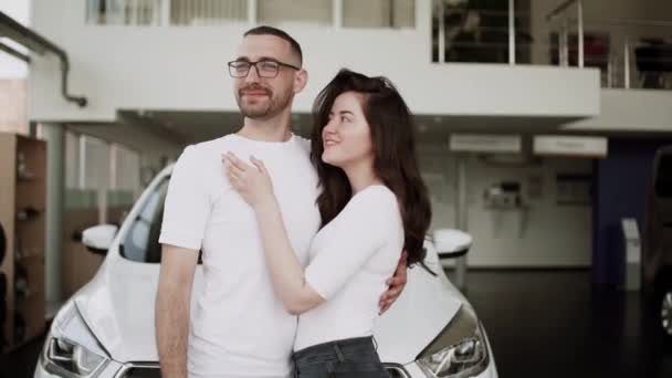 在汽车销售中心 汽车销售人员把新车卖给年轻的家庭 漂亮的年轻夫妇在汽车展示室挑选新车 — 图库视频影像