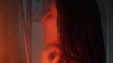 Banyo odasında güzel, sportif bir kadın vücudu. Suyun altında tutkulu bir şekilde el ele tutuşuyor. Yavaş çekimde düşüyor. Neon arkaplanı