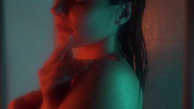 Banyo odasında güzel, sportif bir kadın vücudu. Suyun altında tutkulu bir şekilde el ele tutuşuyor. Yavaş çekimde düşüyor. Neon arkaplanı