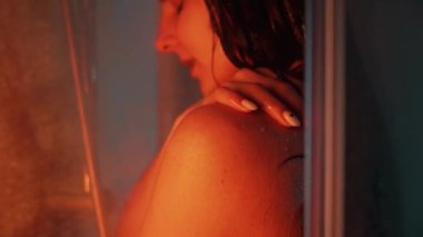 Banyo odasında güzel, sportif bir kadın vücudu. Suyun altında tutkulu bir şekilde el ele tutuşuyor. Yavaş çekimde düşüyor. Neon arkaplanı