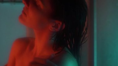 Banyo odasında güzel, sportif bir kadın vücudu. Suyun altında tutkulu bir şekilde el ele tutuşuyor. Yavaş çekimde düşüyor. Neon arkaplanı