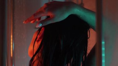 Banyo odasında güzel, sportif bir kadın vücudu. Suyun altında tutkulu bir şekilde el ele tutuşuyor. Yavaş çekimde düşüyor. Neon arkaplanı