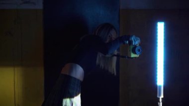 Şık kadın fotoğrafçı, arabanın yanında renkli ışıkta seksi kadın fotoğrafı çekiyor. Modern fotoğrafçılık kavramı.