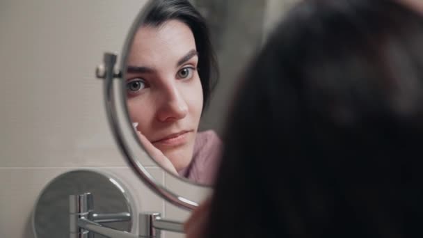若い女性は顔の皮膚の世話をします 美容治療をしている 顔の皮膚にクリームをこすり 朝のルーチン パンピング ホームスパのコンセプト スキンケア化粧品コンセプト — ストック動画