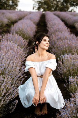 Lavanta tarlasında poz veren beyaz elbiseli genç bir kadın. Lavanta renkli fotoğraf çekimi konsepti.
