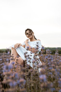 Lavanta tarlasında poz veren beyaz elbiseli genç bir kadın. Lavanta renkli fotoğraf çekimi konsepti.
