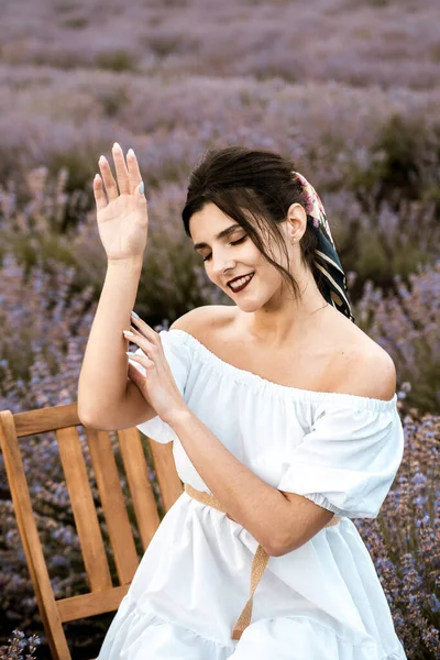 stock image Young woman in a white dress posing in a lavender field.The concept of a photo shoot in lavenders