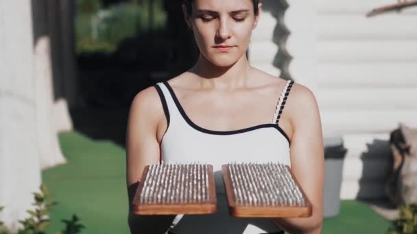 木製のヨガのサドゥーボードに座り 練習と瞑想のための爪を持った女性 代替医療アコースティック 回復強度 芝生の爪で木製のプランクに立つ — ストック動画