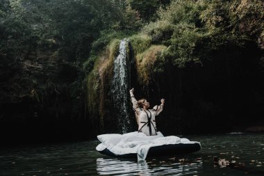 Uyuyan bir kız, güzel bir yerde şişme bir yatakta doğanın çarpıcı manzarası ve şelaleyle uyanır.