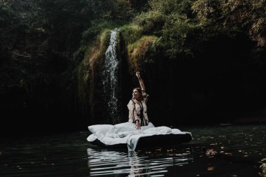 Uyuyan bir kız, güzel bir yerde şişme bir yatakta doğanın çarpıcı manzarası ve şelaleyle uyanır.