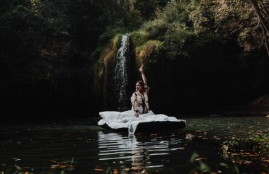 Uyuyan bir kız, güzel bir yerde şişme bir yatakta doğanın çarpıcı manzarası ve şelaleyle uyanır.