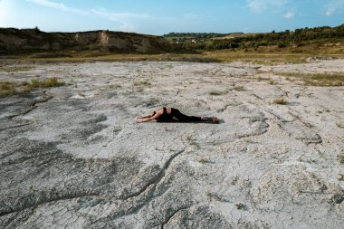 Gün batımında kadın yoga yapıyor ve çölde çivilerin üzerinde duruyor. Yoga ve çivilerin üzerinde durmak kavramı.